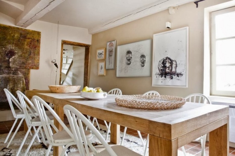 Prosty rustykalny stół z naturalnego drewna,białe skandynawskie krzesła,nowoczesne grafiki na scianach w jadalni z bielonymi belkami z drewna (24957)