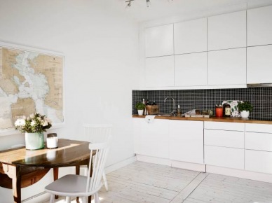 Biała minimalistyczna kuchnia z czarną glazurą na ścianie,drewniany składany stół i białe skandynawskie krzesła z drewna w kuchni (26366)