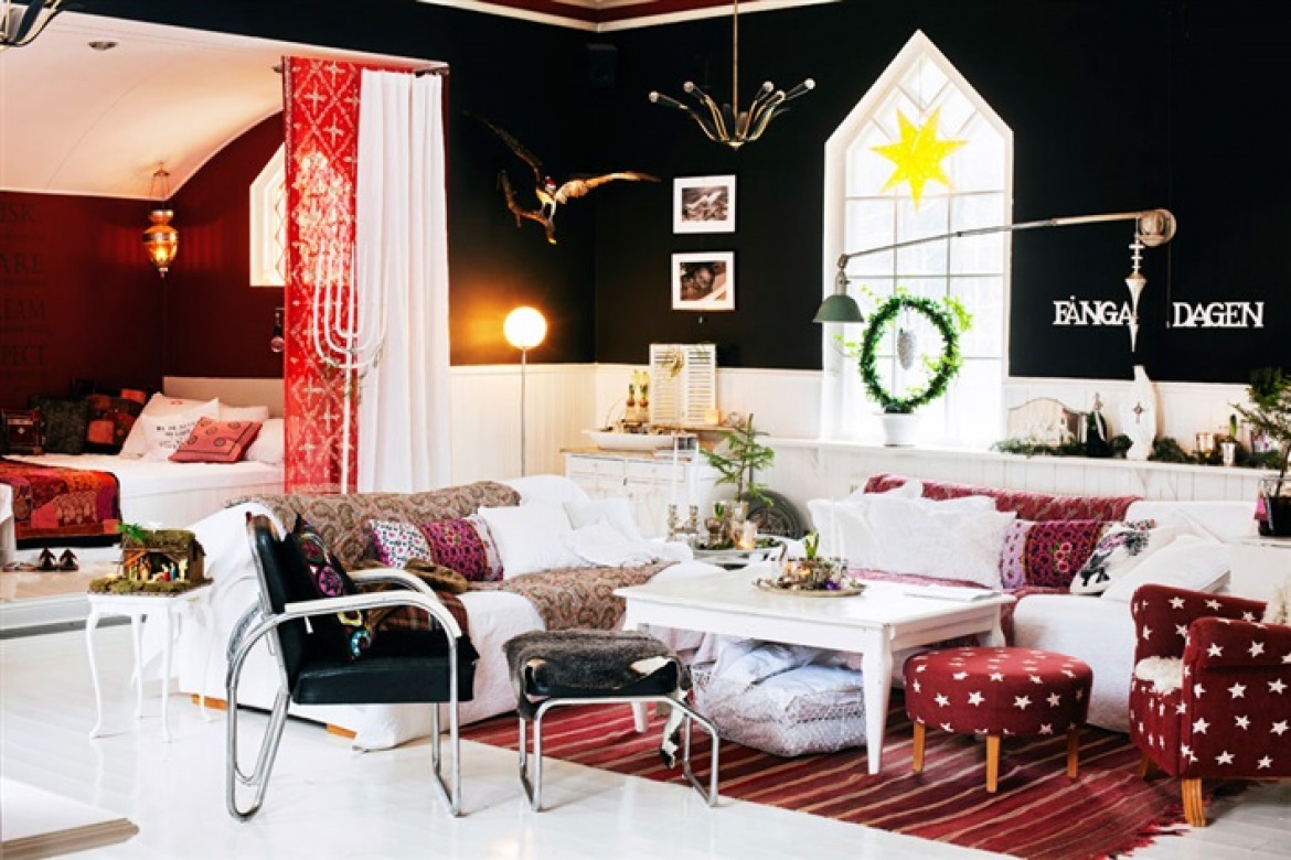 Czerwone i czarne ściany w skandynawskim salonie z biała sofą,czarnymi krzesłami i czerwonym fotelem z podnóżkiem w białe gwiazdki w świątecznej dekoracji (27504)