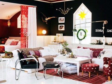 Czerwone i czarne ściany w skandynawskim salonie z biała sofą,czarnymi krzesłami i czerwonym fotelem z podnóżkiem w białe gwiazdki w świątecznej dekoracji (27504)