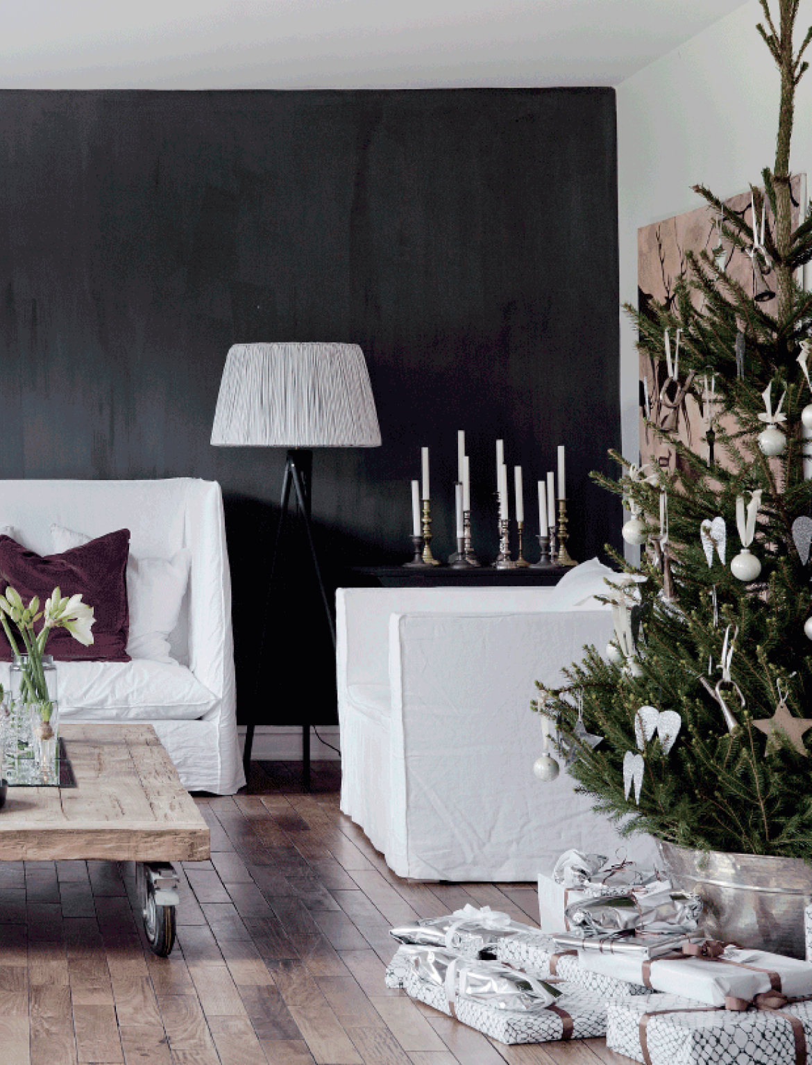 Białe sofy i fotele w lnianych pokrowcach,czarna ściana,stolik z palety na kółkach,zielona choinka w białych dekoracjach świątecznych (47764)