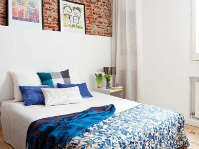 Niebieska narzuta na łóżko z czerwoną cegłą na ścianie idealnie wpisuje się w charakter nowoczesnej,ale jakże przytulnej sypialni.Biała dobudowa ciekawie dzieli przestrzeń i pozwala na postawienie ulubionych zdjęć czy obrazów, ten sam zabieg zastosowano w...