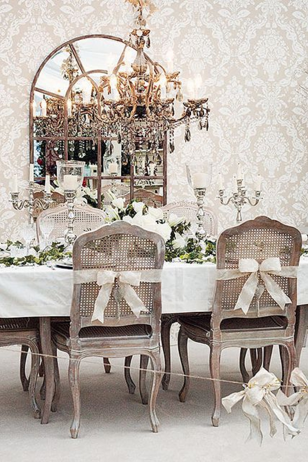 Prowansalski żyrandol z paciorkami,francuskie ozdobne świeczniki na światecznym stole,francuskie dzielone lustro i prowansalskie krzesła bielone z rattanowymi oparciami przewiązanymi białymi wstążkami (27434)