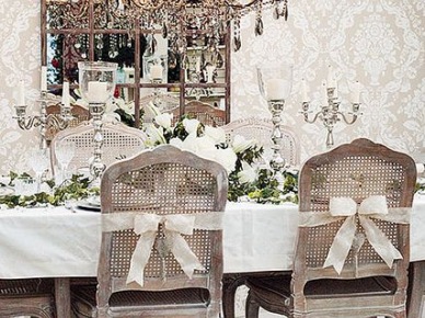 Prowansalski żyrandol z paciorkami,francuskie ozdobne świeczniki na światecznym stole,francuskie dzielone lustro i prowansalskie krzesła bielone z rattanowymi oparciami przewiązanymi białymi wstążkami (27434)