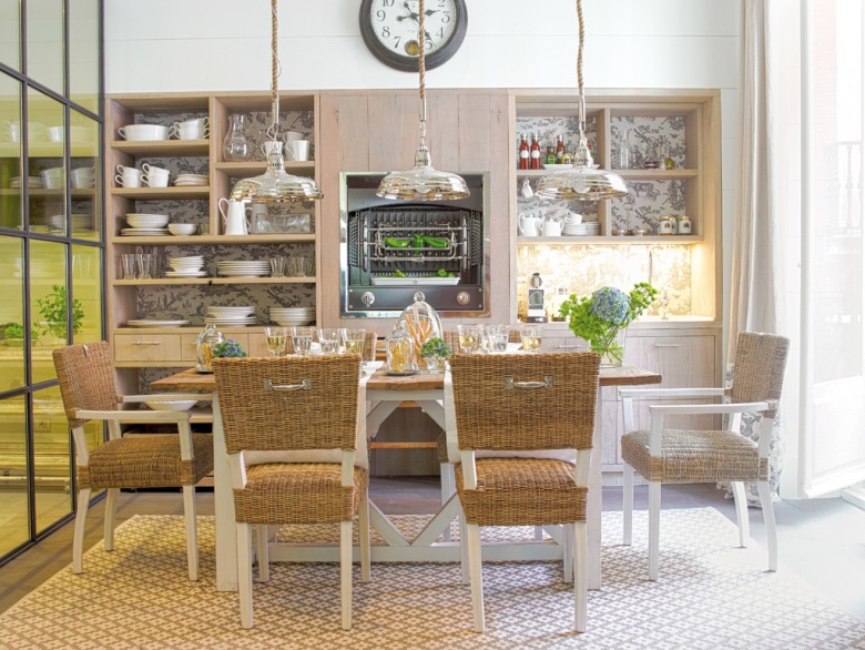 Biały tradycyjny stół z drewnianym blatem,drewniane krzesła z plecionymi siedziskami i oparciami,chromoniklowane rustykalne lampy wiszące,otwarte półki i przeszklona ściana w dużej kuchni (26418)