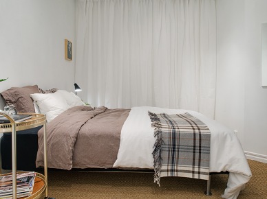 Białe zasłony,beżowa pościel i kraciastay pled w aranżacji skandynawskiej sypialni (22567)