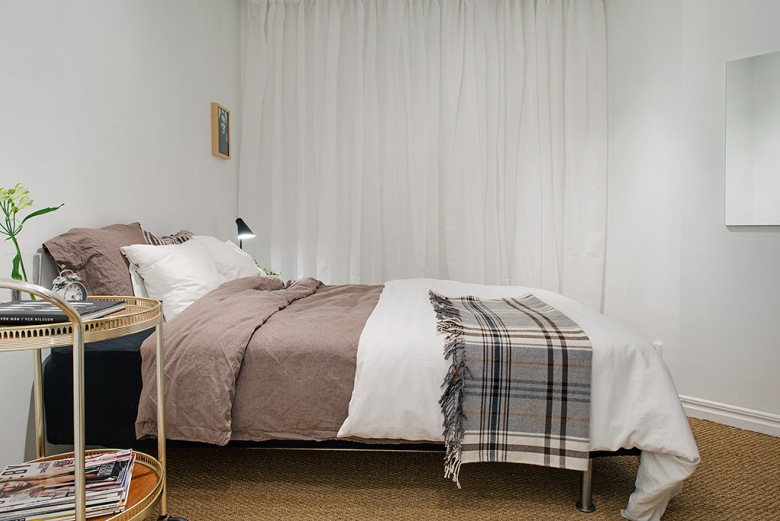 Białe zasłony,beżowa pościel i kraciastay pled w aranżacji skandynawskiej sypialni (22567)