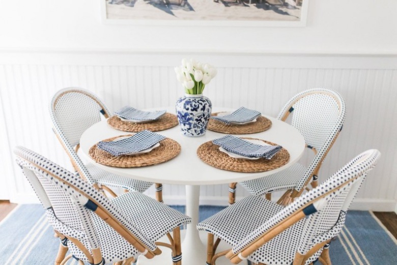 Drewniane nogi i ramy krzeseł z wyplatanymi siedziskami i wiązaniami w niebieskim kolorze zdobią jadalnię, nadając jej...