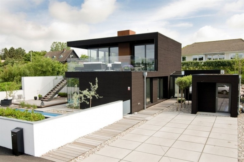 duński dom w nowoczesnej, czarnej bryle ujmuje geometrią, estetyką i czarnym dizajnem - duże ściany w szkle nadają mu...