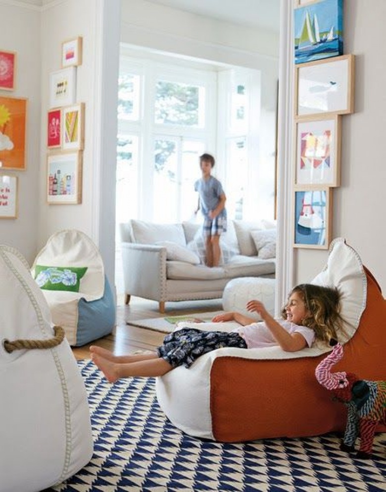 Jasny pokój dziecięcy udekorowany duża ilością kolorowych obrazków. Na pierwszym planie duża pufa, która jest idealnym...
