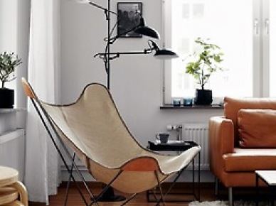Dizajnerski brązowy fotel motyl, czarna lampa podłogowa z trzema abażurami,kwadratowy czarny stolik pomocniczy z tacą,ruda skórzana sofa w salonie (25827)