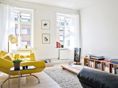 Żółta nowoczesna sofa w białym salonie skandynawskim z niskim stolikiem i pólkami  z drewna (25683)