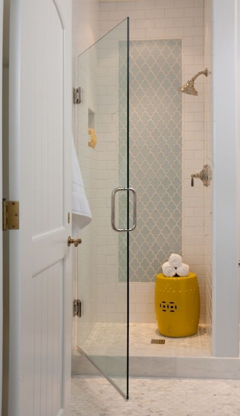 Mała skromna łazienka, w której stonowaną białą aranżację urozmaicono żółtymi dodatkami oraz lekkim wzorem tworzącym jakby panel ścienny w kabinie prysznicowej. Skandynawska prostota i niewielkie rozmiary tworzą z tego wnętrza funkcjonalny, nieco minimalistyczny 