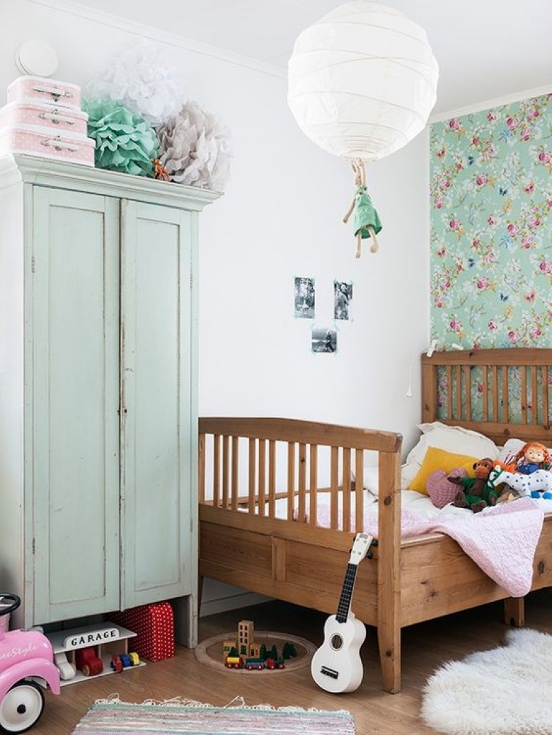 Drewniane łóżko oraz pomalowana miętową farbą szafa wprowadzają naturalny charakter do pokoju dziecięcego. Kwiatowy...