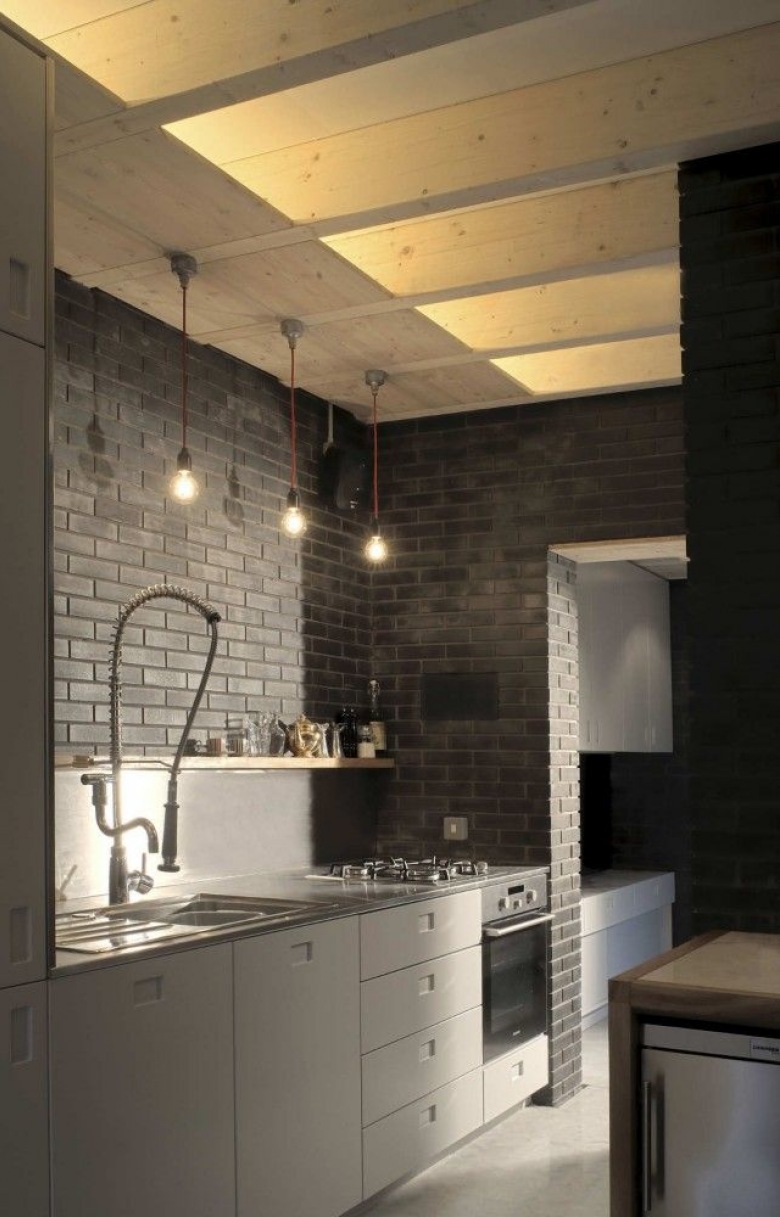 Nowoczesna szara kuchnia z ciemnoszarą cegłą na ścianie, drewnianym sufitem i żarówkami na kablach (25638)