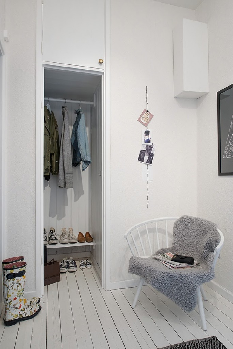 Mała garderoba we wnęce w przedpokoju,biały drewniany fotel skandynawski,biale malowane deski na podłodze (25805)