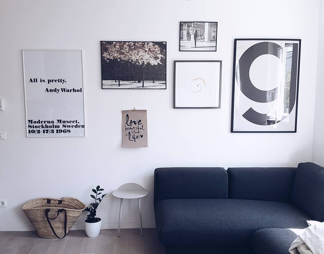 W aranżacji salonu dominuje ciemnoszara sofa, do której dopasowano drobne dekoracje. Zdjęcia i typografia rozłożone w...